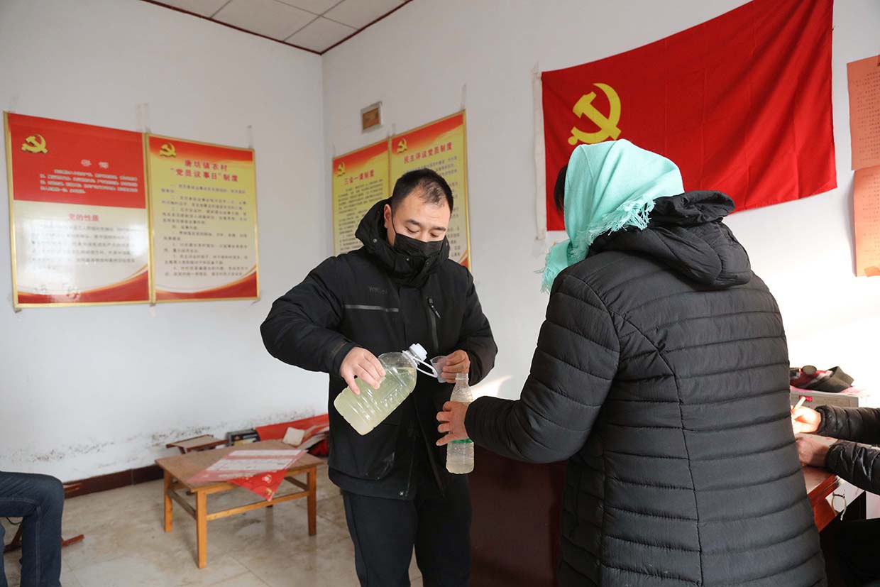 包村李书记为村民分发政府发放的消毒液,并告知村民使用方法。